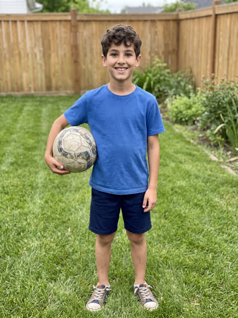 Example photo: full length shot of a boy in a backyard with a soccer ball